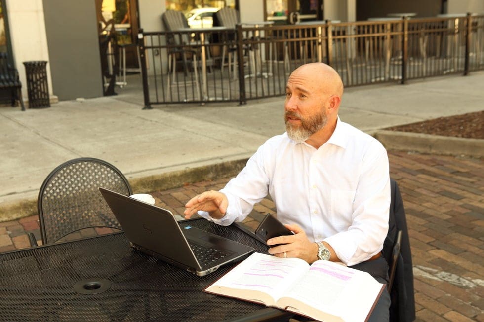 Family law attorney AJ Grossman sitting at table outside discussing a case with his client