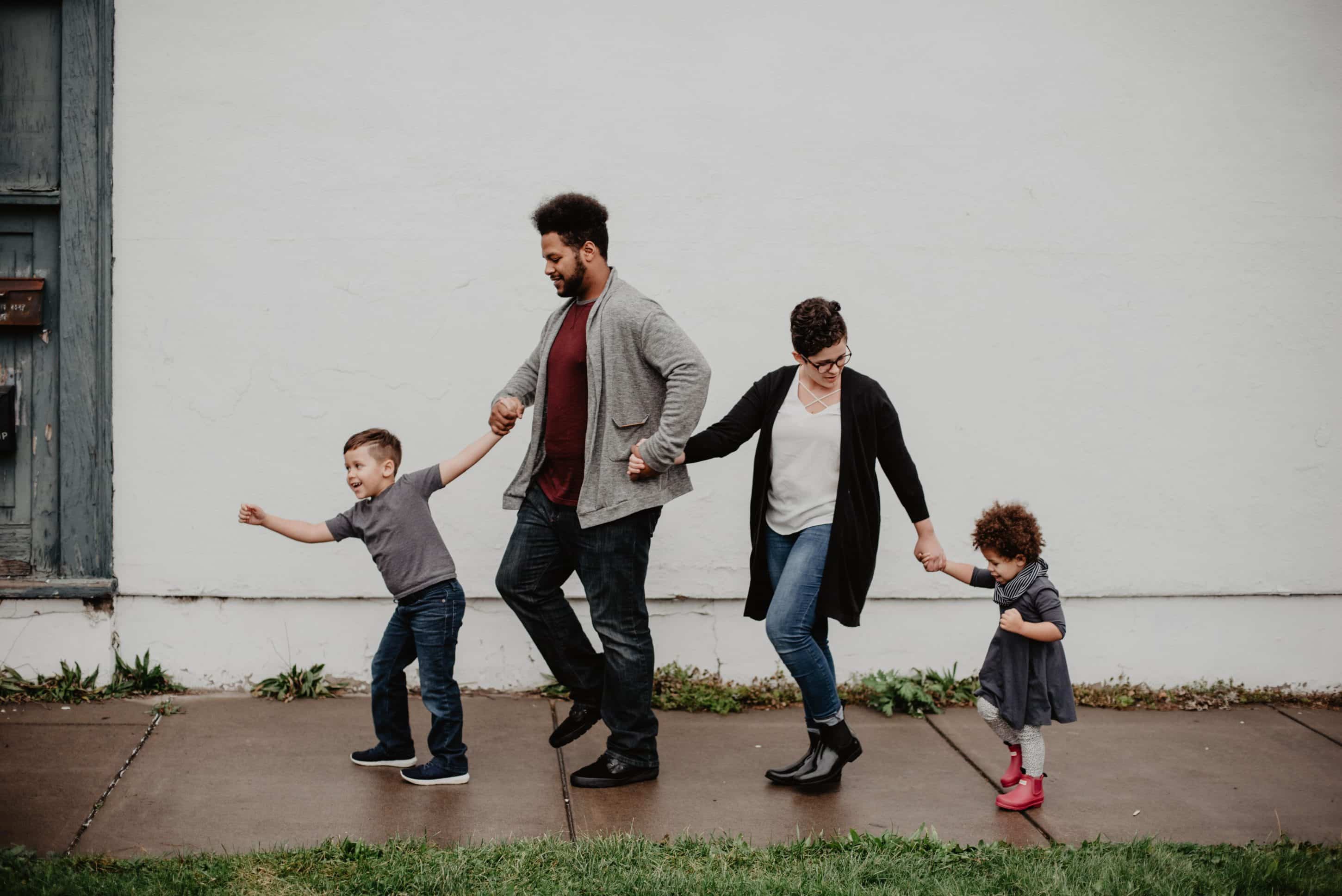 Parents with two kids all holding hands while walking
