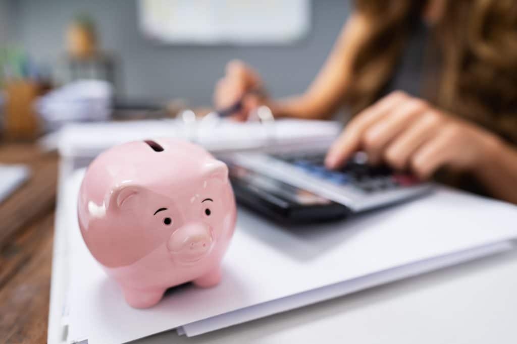 Woman budgeting with calculator and piggy bank