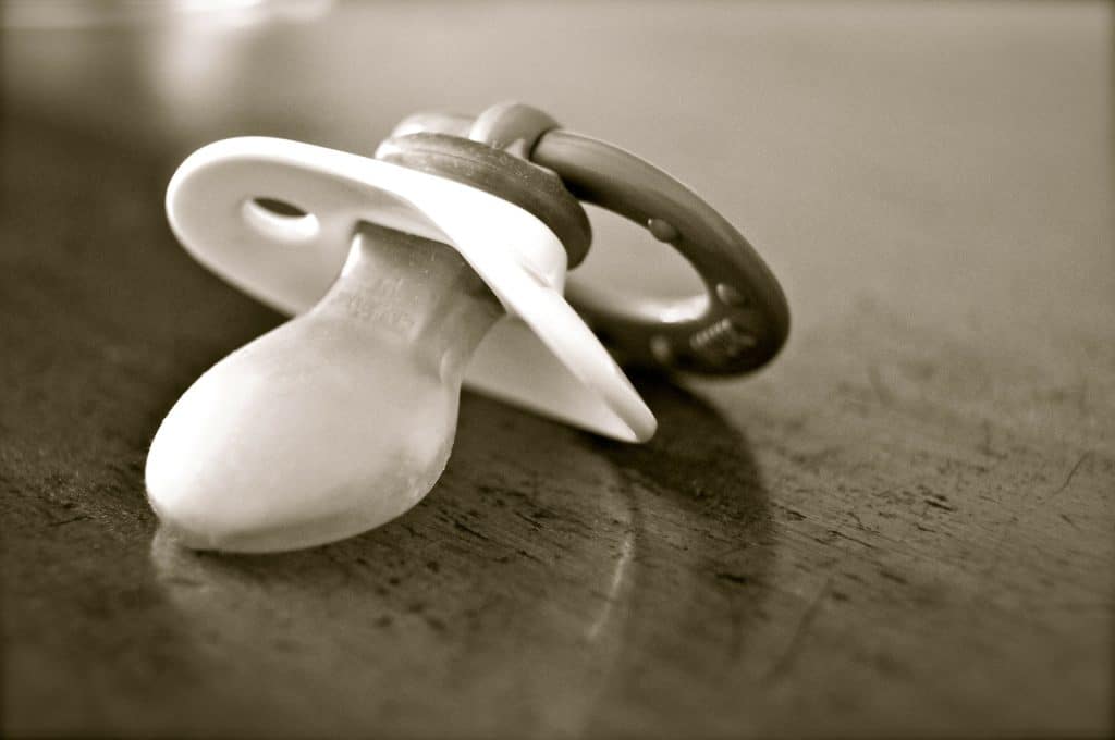 sepia toned photo of pacifier on table