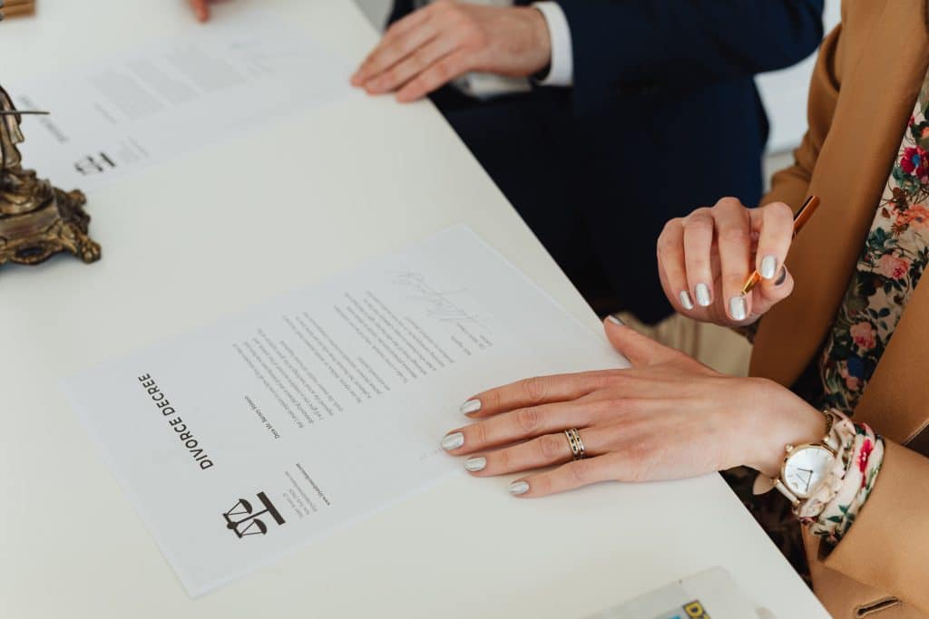 closeup of man's and woman's hands signing divorce decree