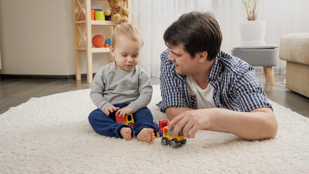 father playing on floor with baby