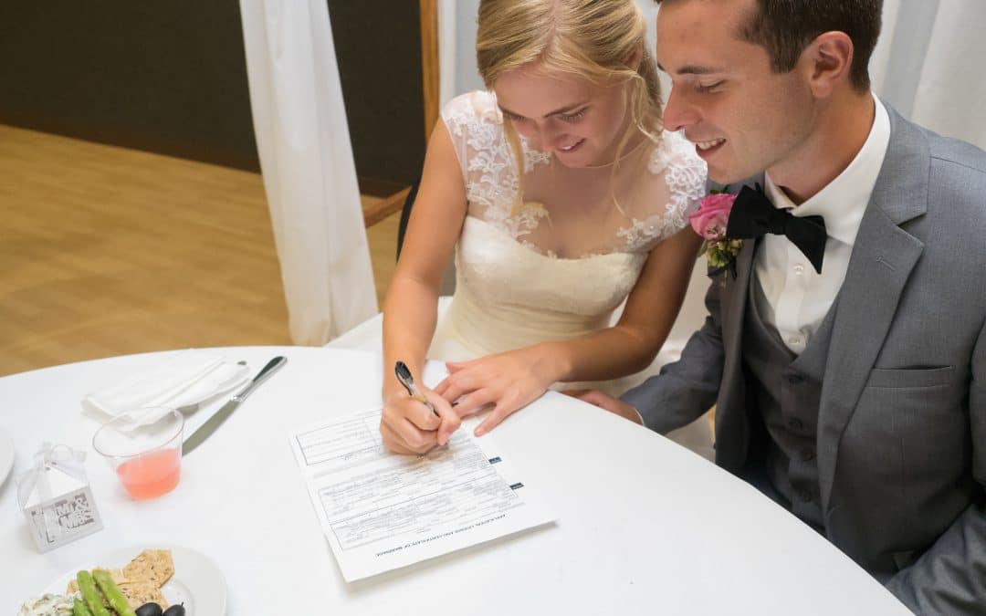 A bride and groom signing a prenuptial agreement on their wedding day