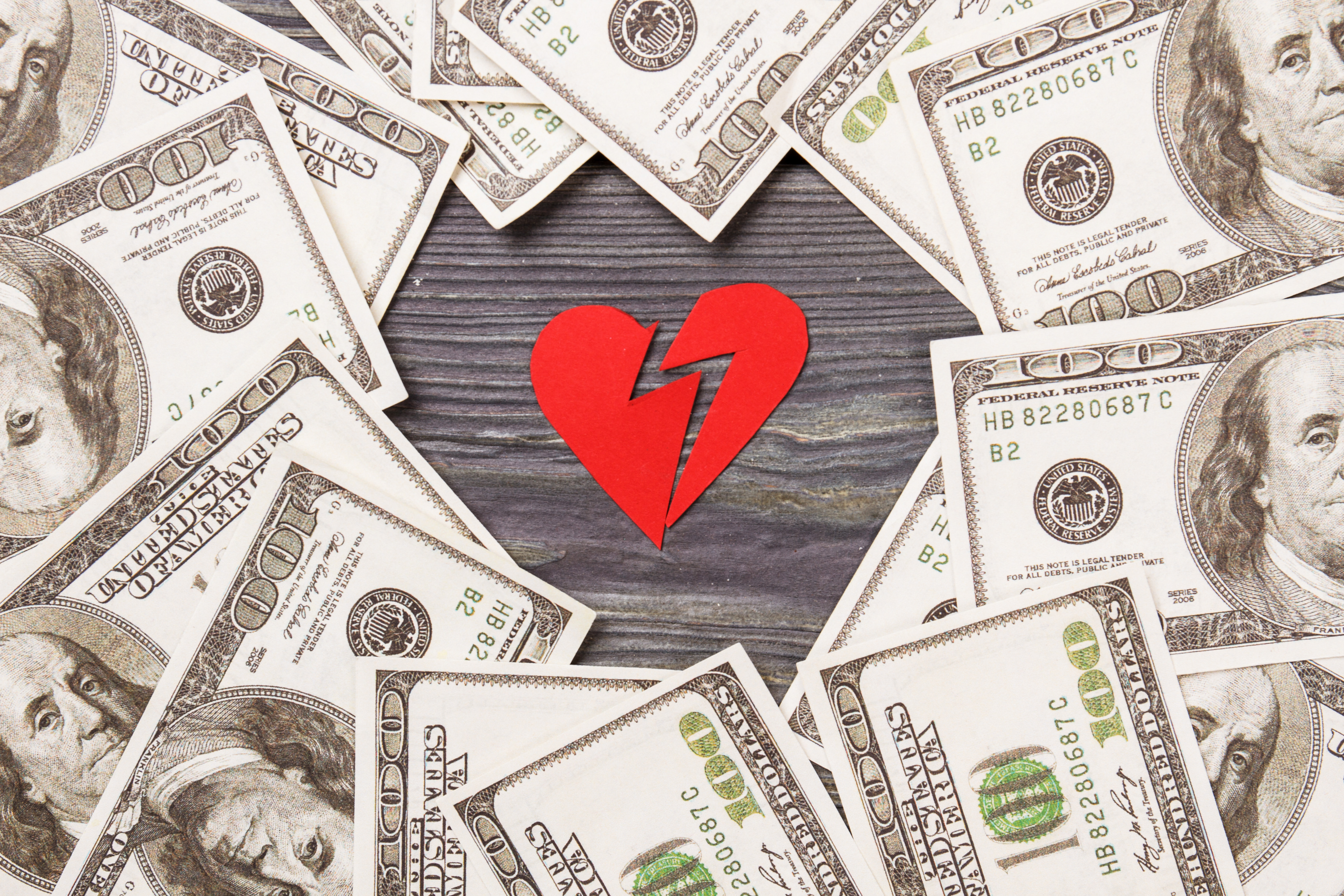 broken paper heart surrounded by money