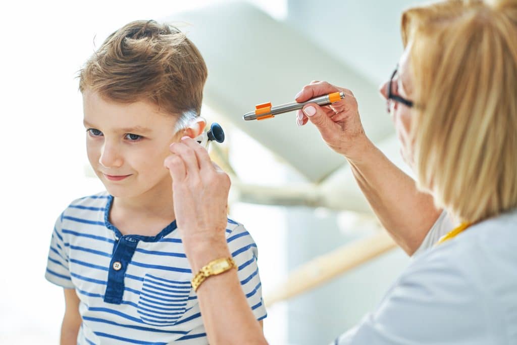 Pediatrician looking into boy's ear