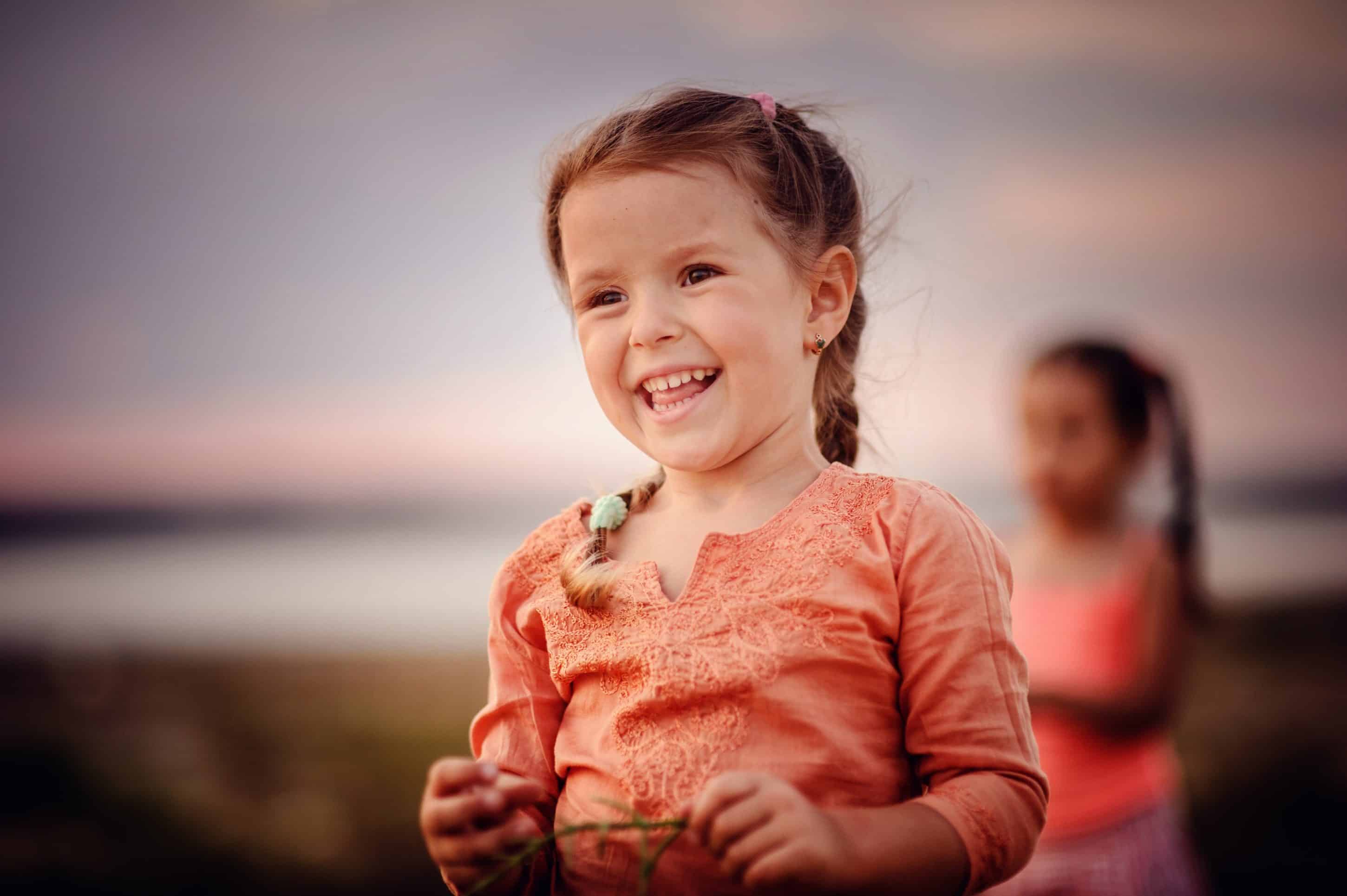 toddler girl smiling while holding a flower