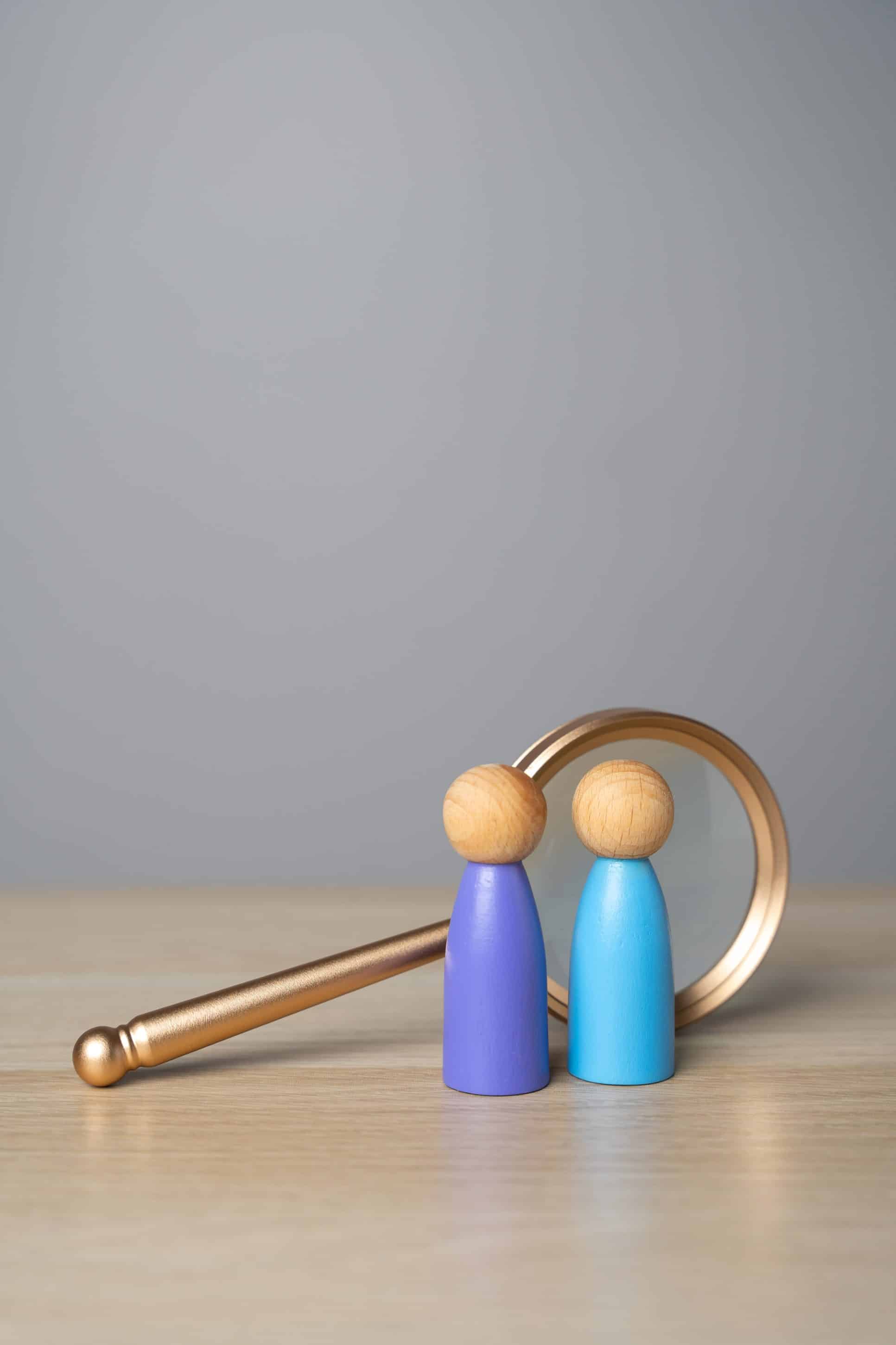 two abstract wooden figures in front of magnifying glass