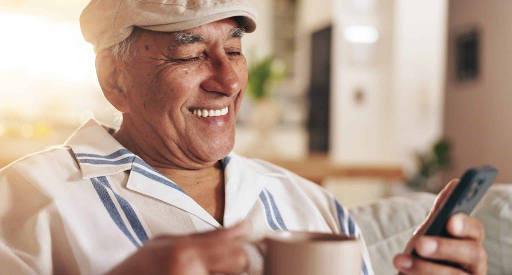 senior man drinking coffee and looking at phone
